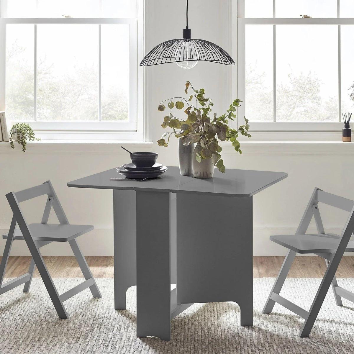 Light grey gateleg table with two matching chairs in bright dining room setting