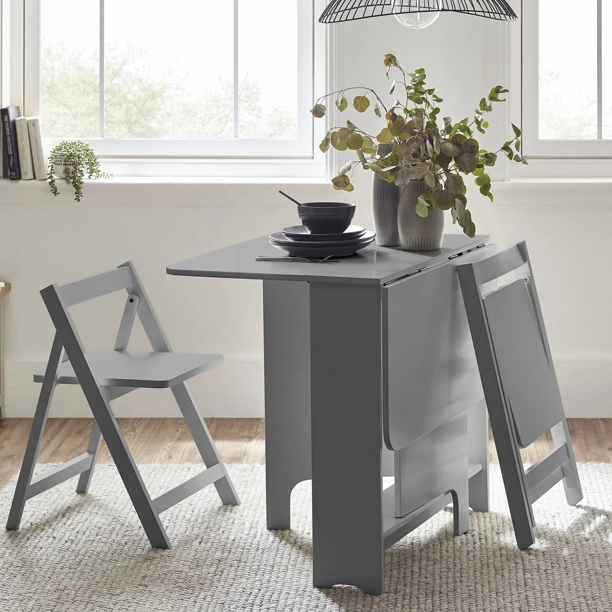 Light grey gateleg dining table with two folding chairs in a modern bright room