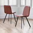 Brown faux leather dining chairs with black metal legs on wood floor in bright room