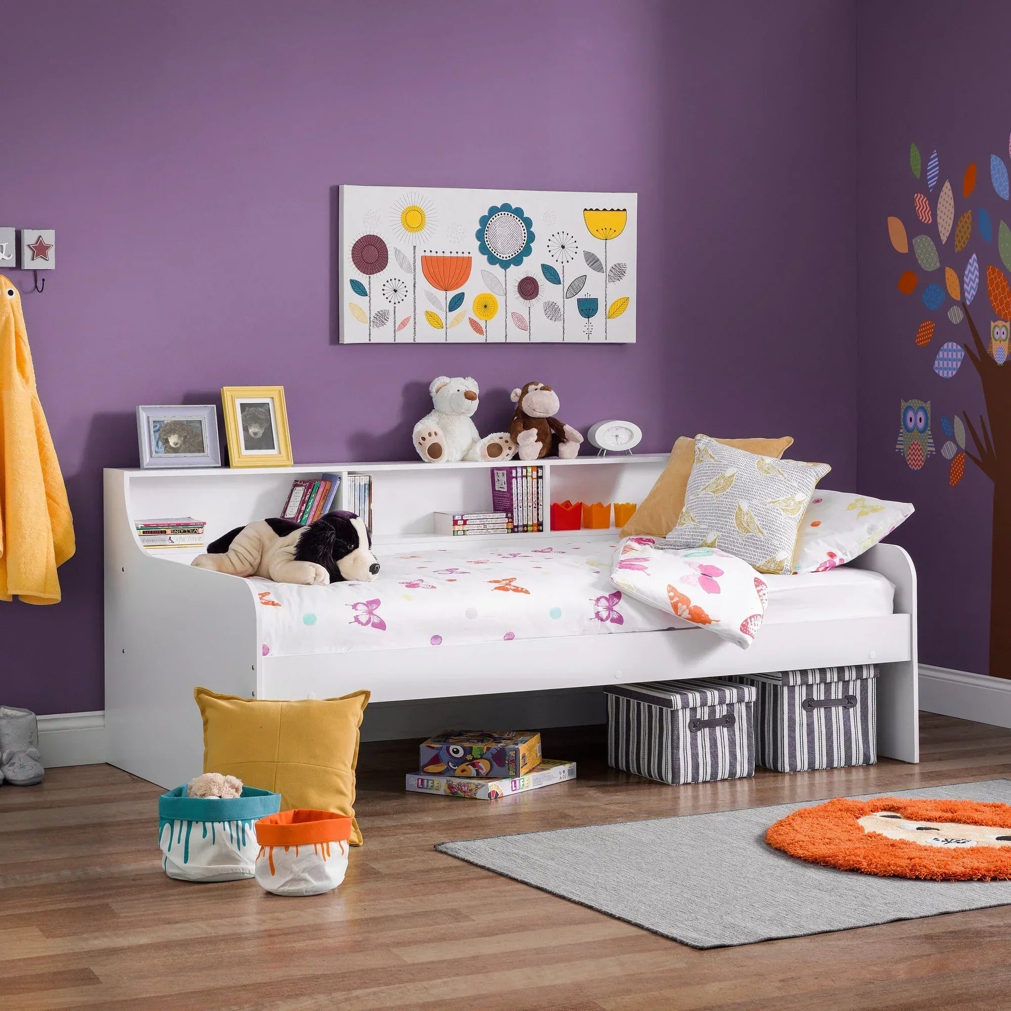 White daybed with storage shelves in a child’s bedroom with purple walls and floral art