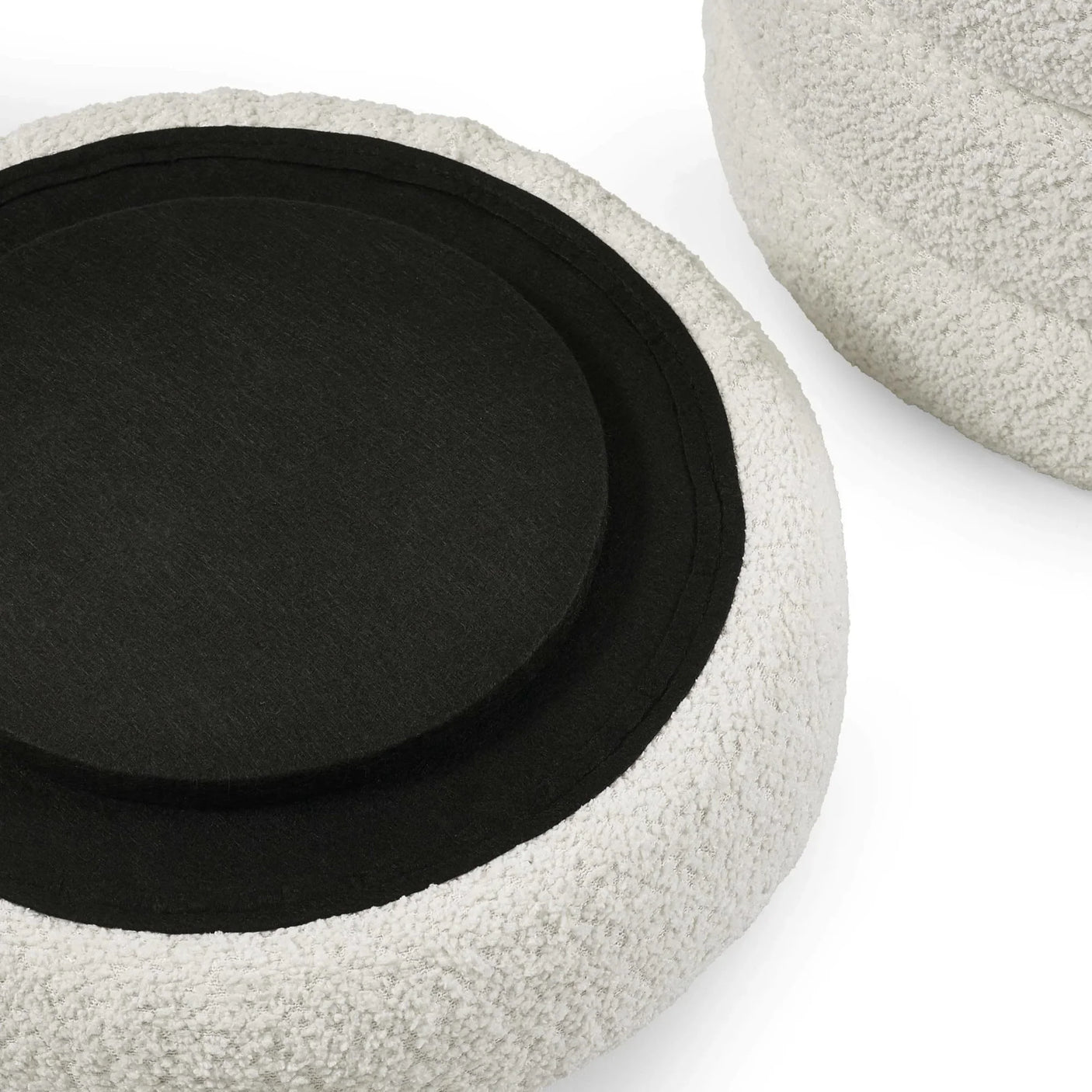 Round boucle ottoman with black fabric base and white textured upholstery close up