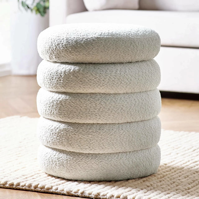 Cream boucle pouffe with stacked cushion design on textured rug in living room