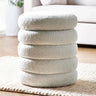 Cream boucle pouffe with stacked cushion design on textured rug in living room