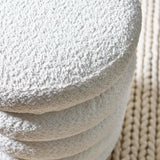 Round cream bouclé stool detail with textured upholstery on woven rug