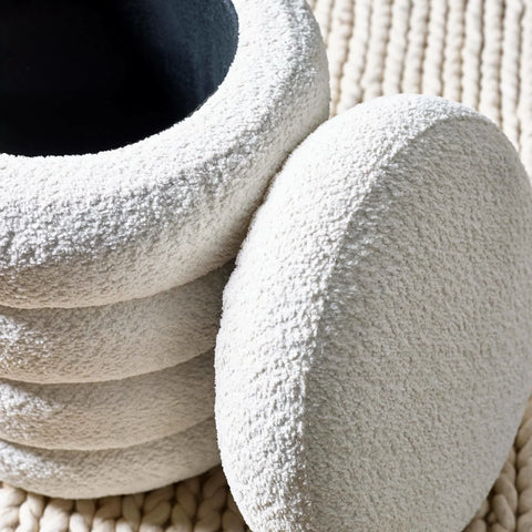 Textured cream boucle ottoman with stacked circular shape on woven rug