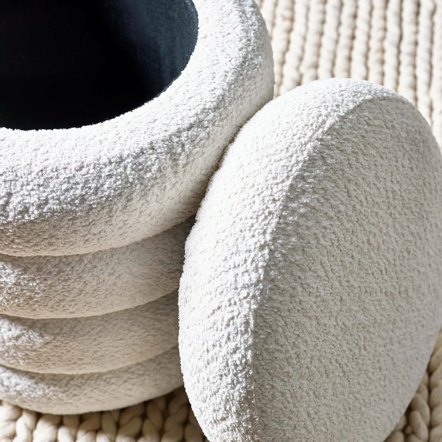 Textured cream boucle ottoman with stacked circular shape on woven rug