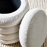 Textured cream boucle ottoman with stacked circular shape on woven rug