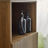 Close-up of brown wooden cabinet with two black pump bottles in open upper shelf.