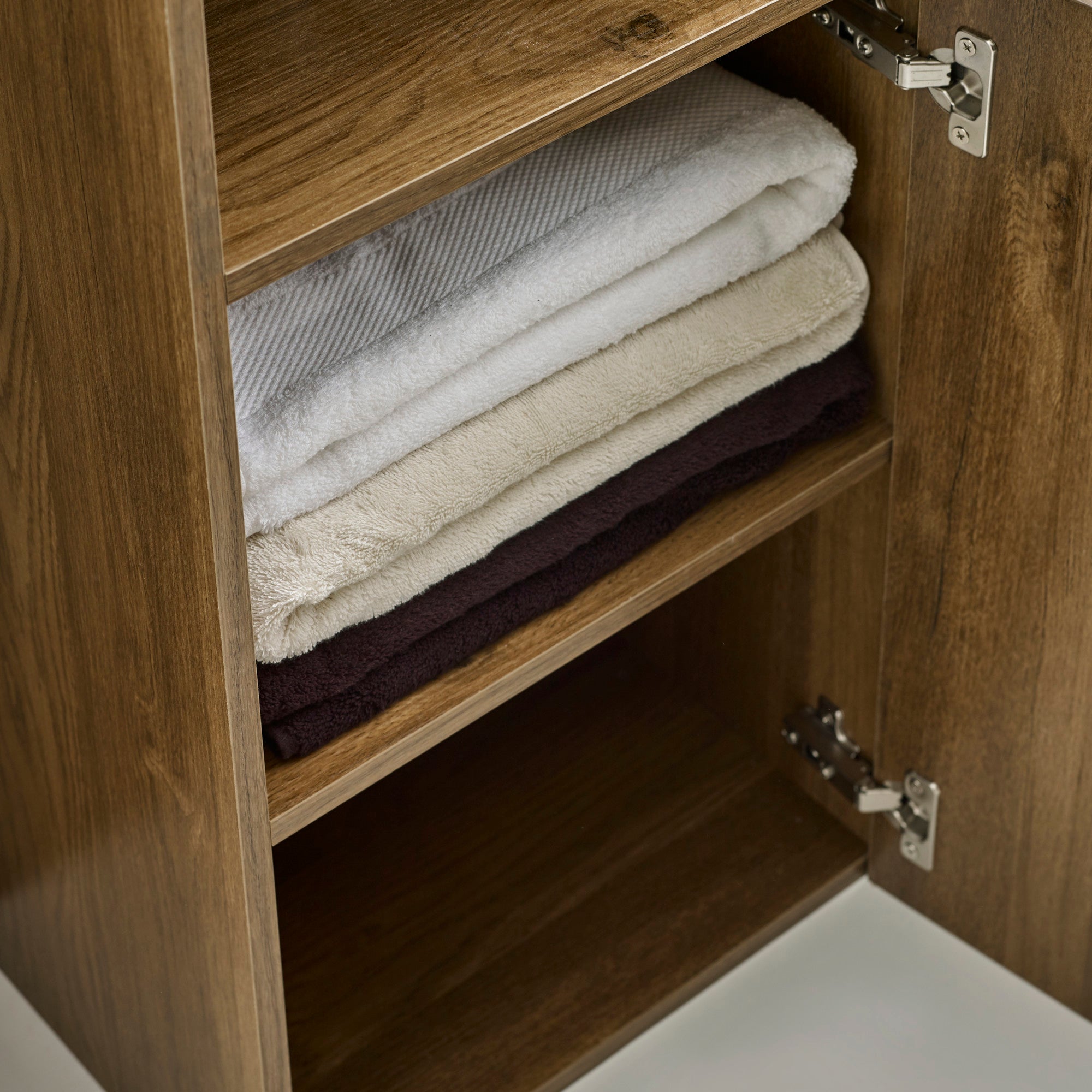 Open cabinet door revealing folded towels on wooden shelf with metal hinges visible.