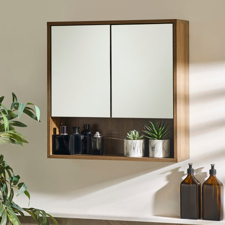 Wall-mounted brown wood bathroom cabinet with two mirrored doors and open shelf holding bottles and plants.
