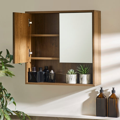 Brown wood bathroom cabinet with left door open, showing empty shelves; mirrored right door and open shelf below.
