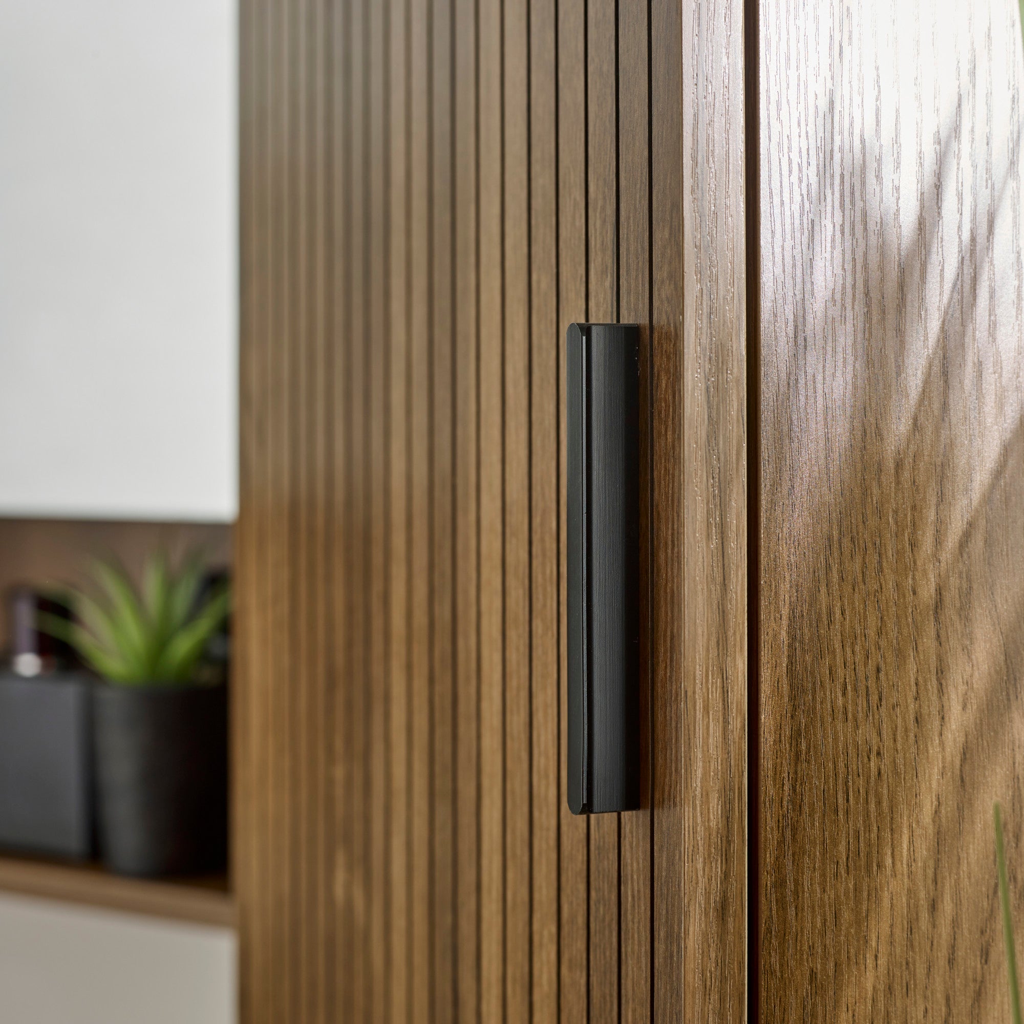 Tall walnut bathroom cabinet with textured slatted doors and open shelves displayed in modern bathroom setting