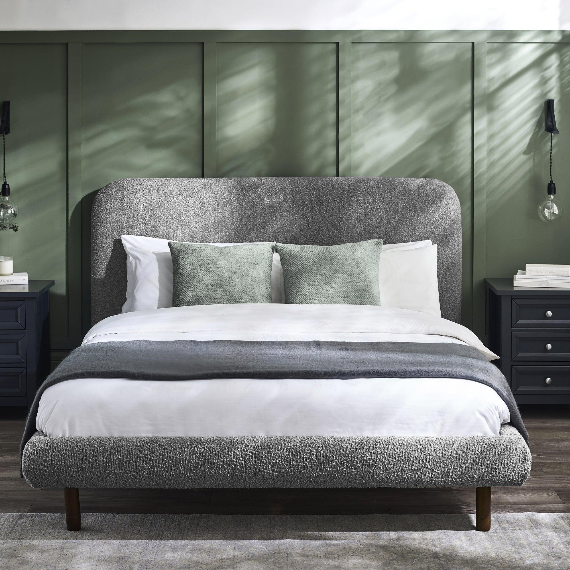 Grey upholstered Hannah bed 135cm with green cushions, beside navy bedside tables