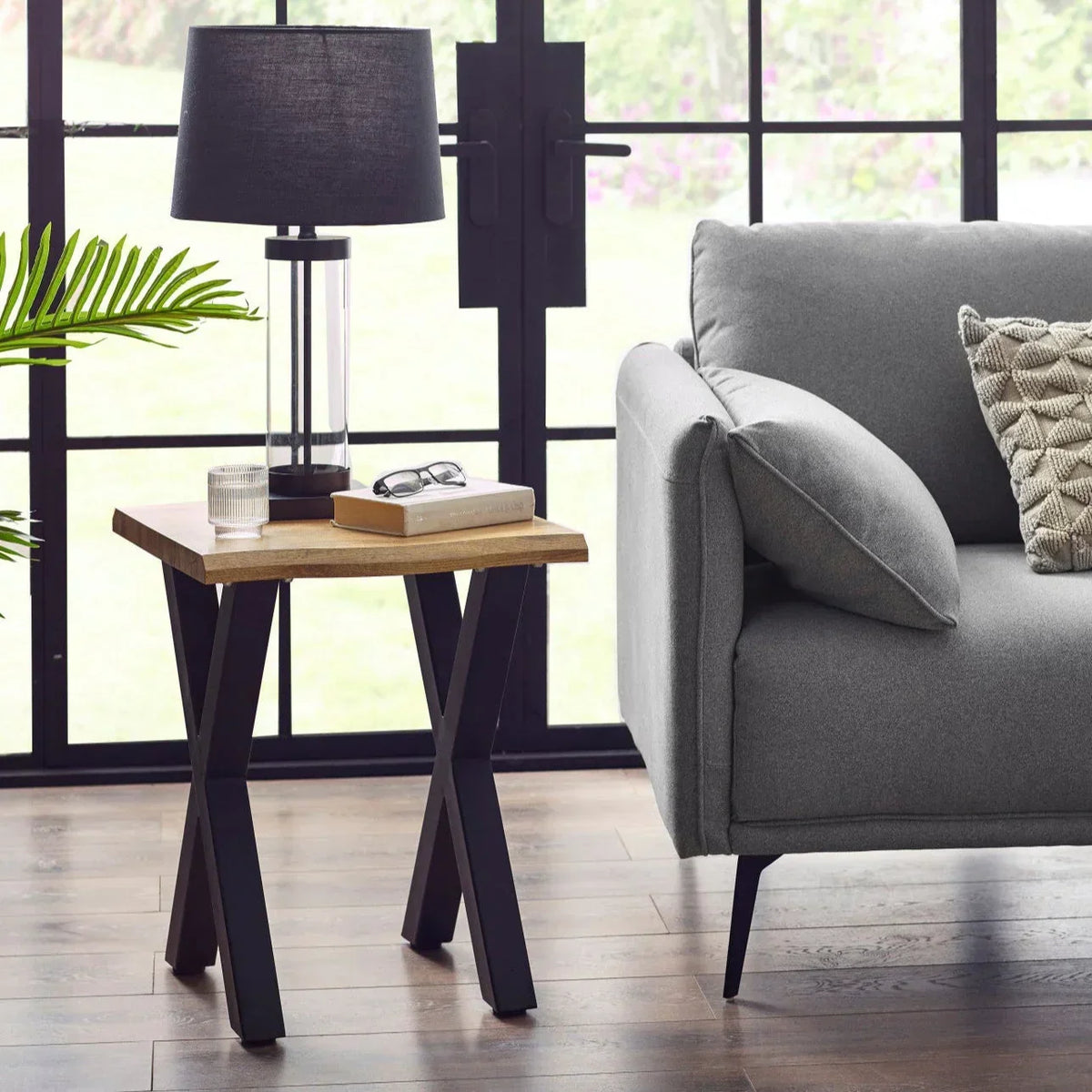 wooden lamp table with black metal legs beside grey sofa in modern living room