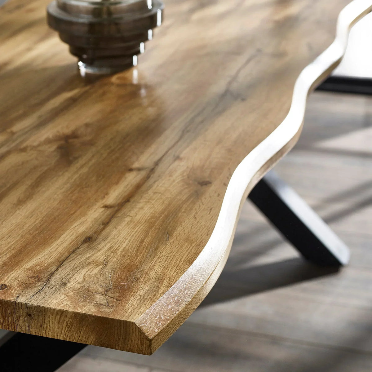 Oak dining table closeup showing live edge wood grain and sturdy black metal legs