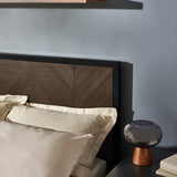 Angled view of dark wood herringbone headboard with cream pillows and bedside lamp on dark gray table