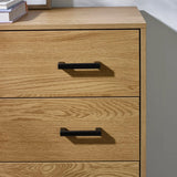Oak wood chest of drawers with black metal handles, close-up of top drawers
