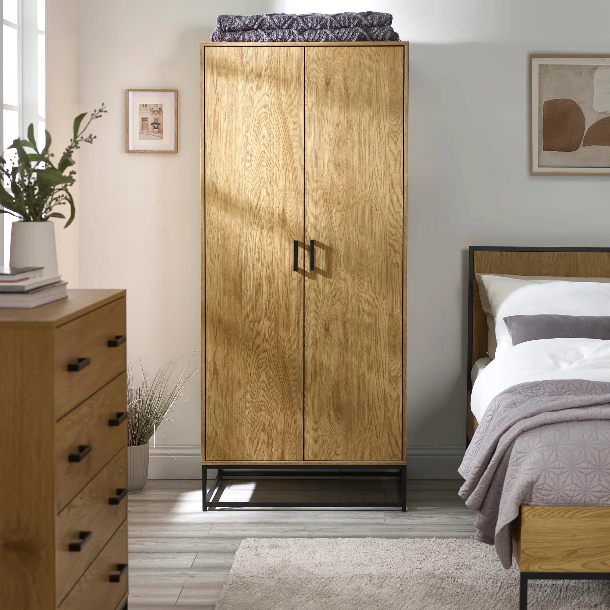 Oak wardrobe with black metal frame and handles in modern bedroom setting