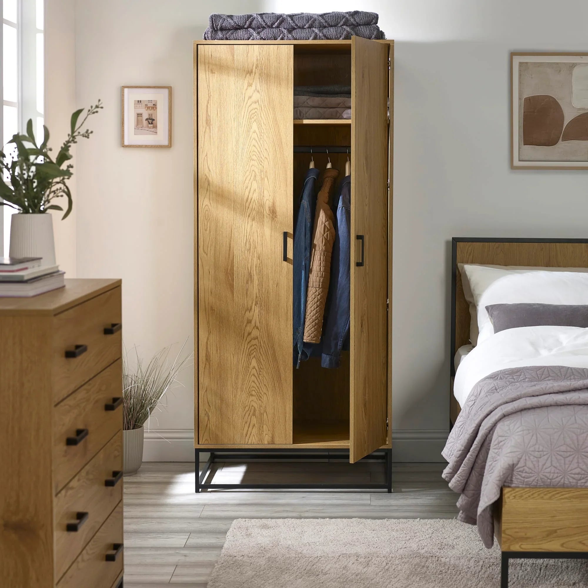 Oak wardrobe with black metal frame, partially open, in modern bedroom setting