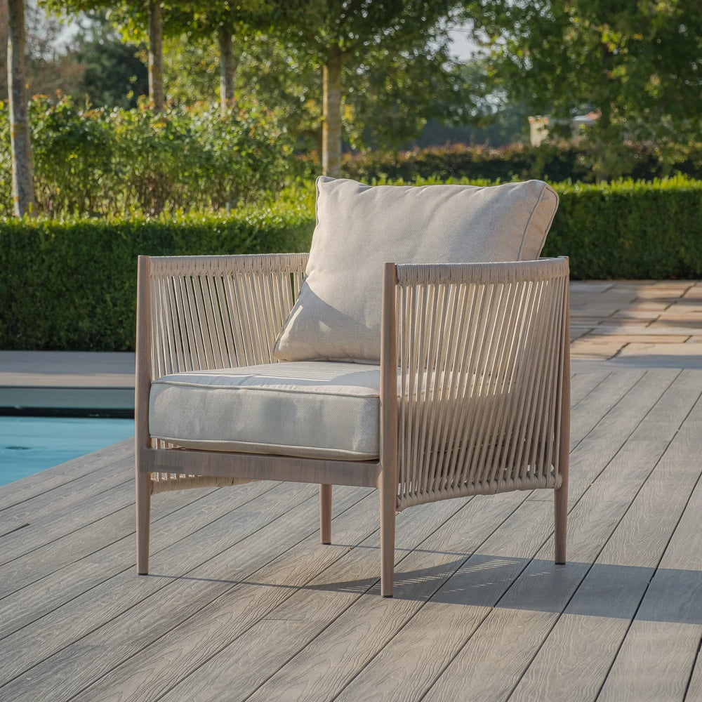 Rope outdoor armchair with beige cushions on deck beside swimming pool