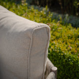 Close-up of outdoor sofa cushion in beige textured fabric with greenery background