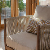 Beige rope accent armchair with textured seat cushion and geometric patterned pillow