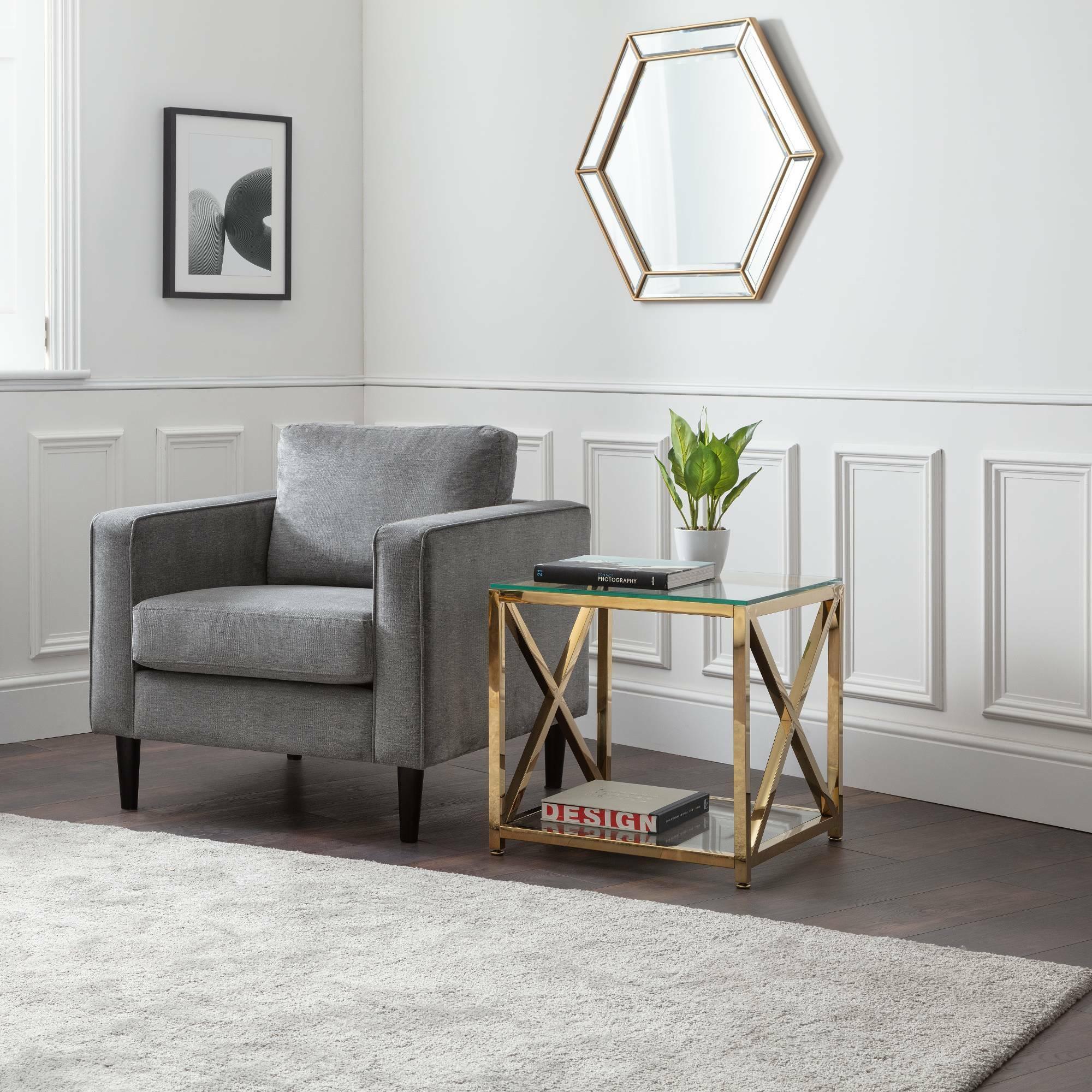 Dark grey chenille armchair in modern living room with gold glass side table and wall decor
