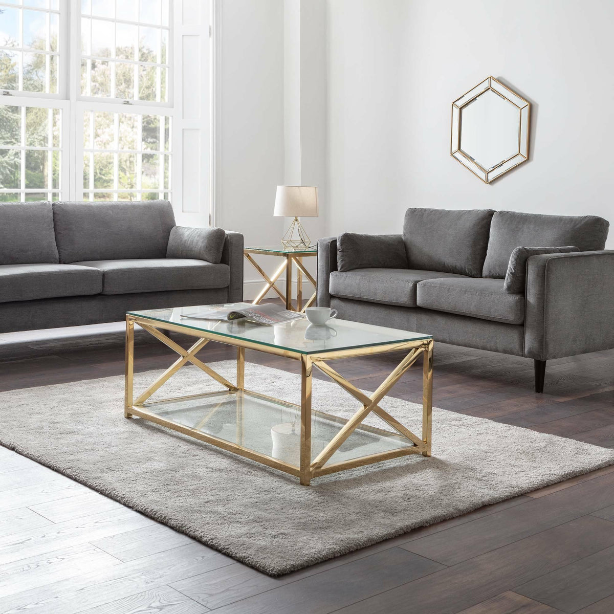 Dark grey chenille 2 seater and 3 seater sofas with gold glass coffee table in bright living room
