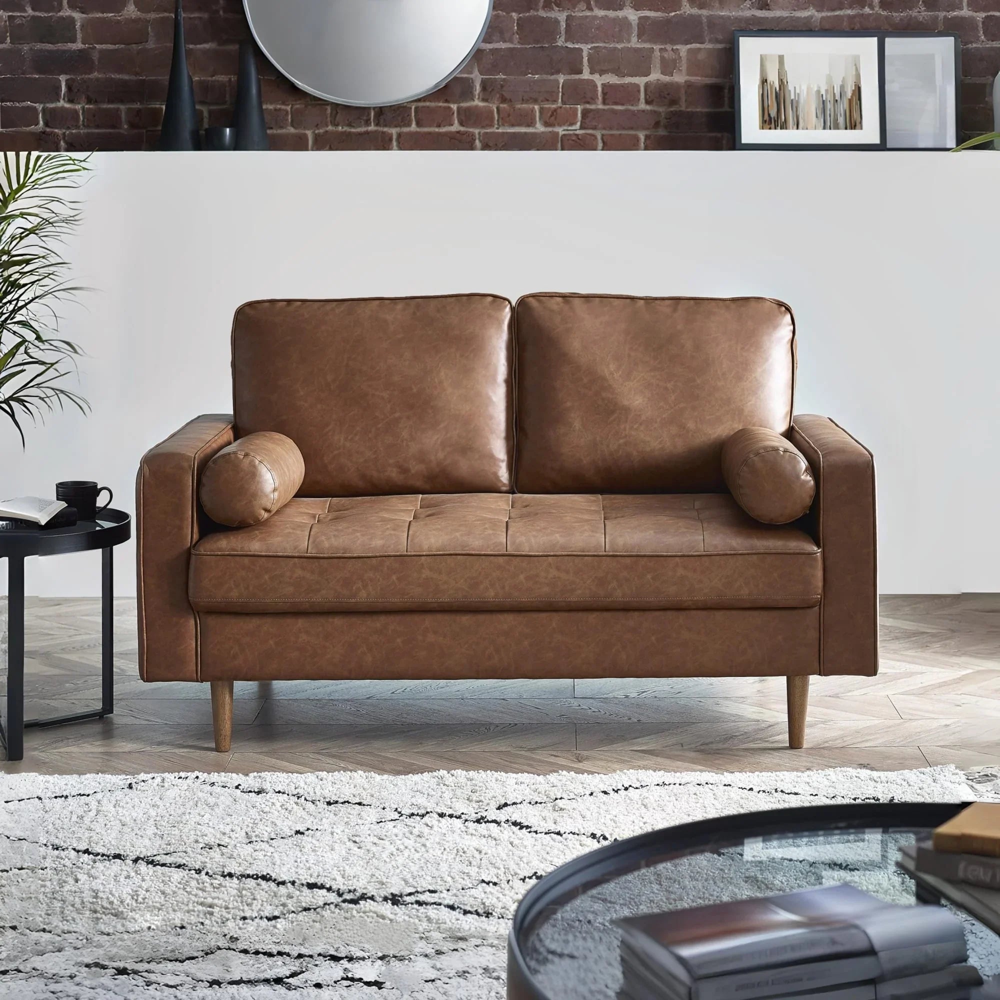 Brown leather sofa with two seat cushions and bolster pillows in modern living room