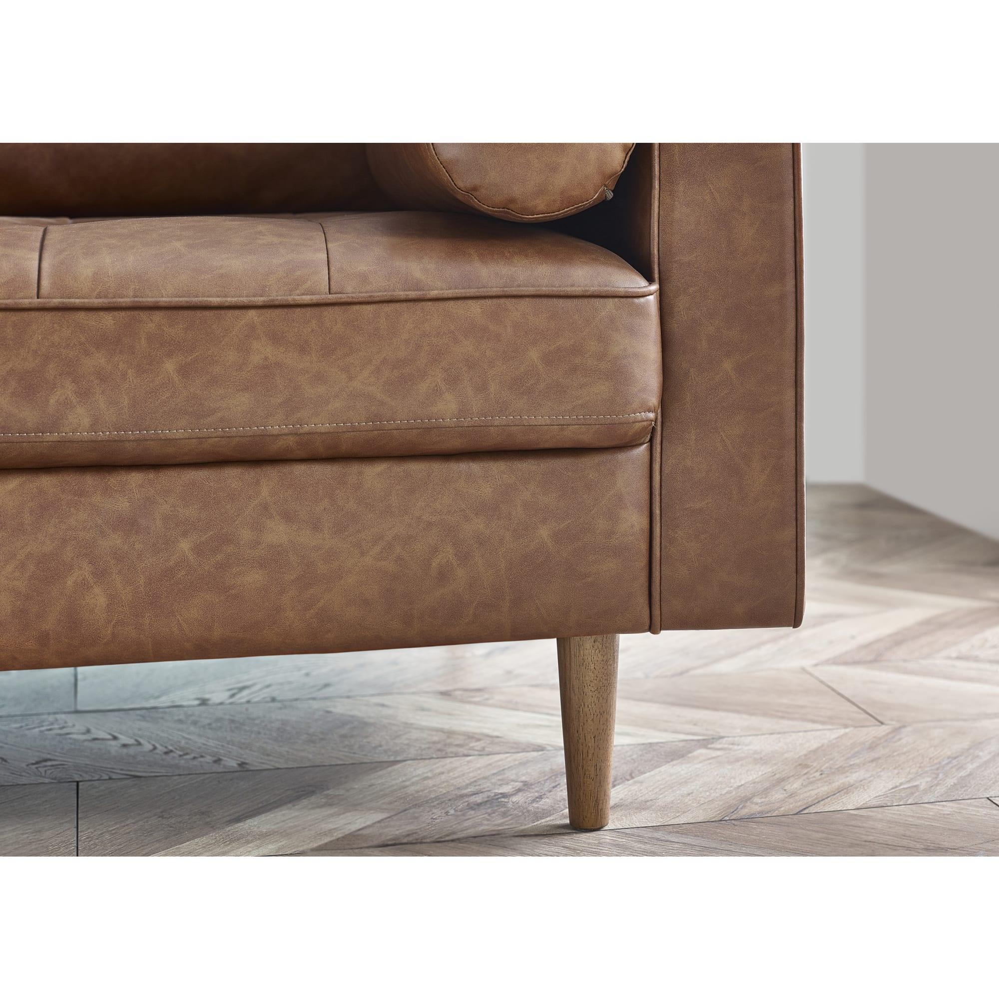 Brown leather sofa corner with wooden leg on chevron wood flooring