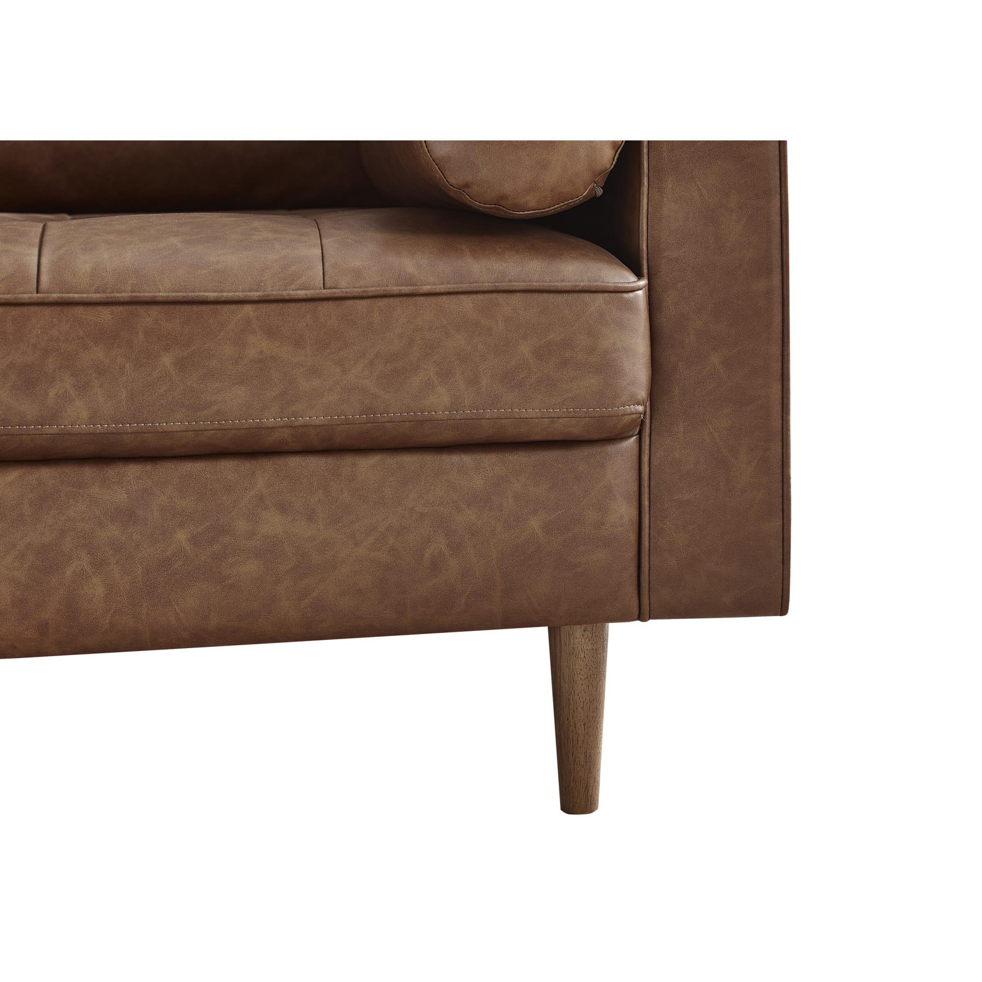 Close-up of brown leather sofa with wooden leg and stitched cushion detail