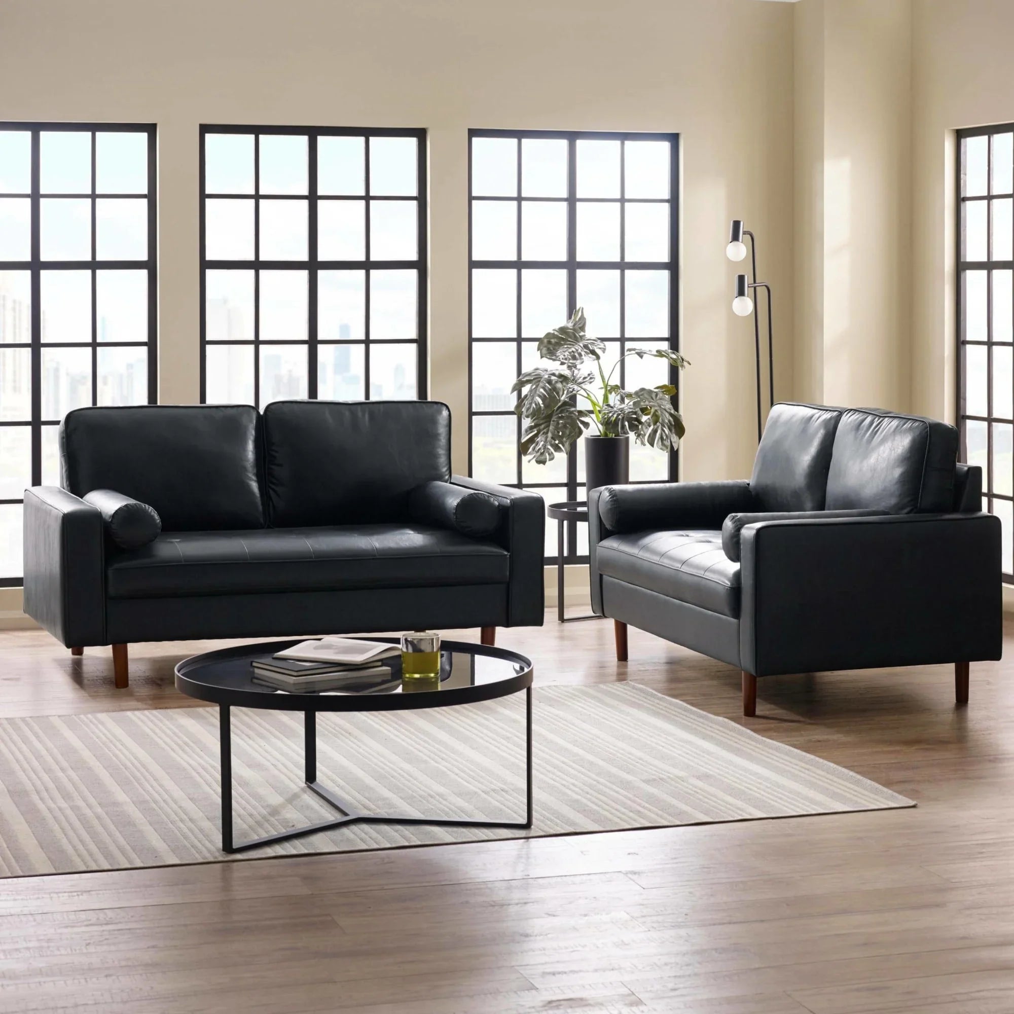Black leather sofa set with wooden legs in modern living room with round coffee table