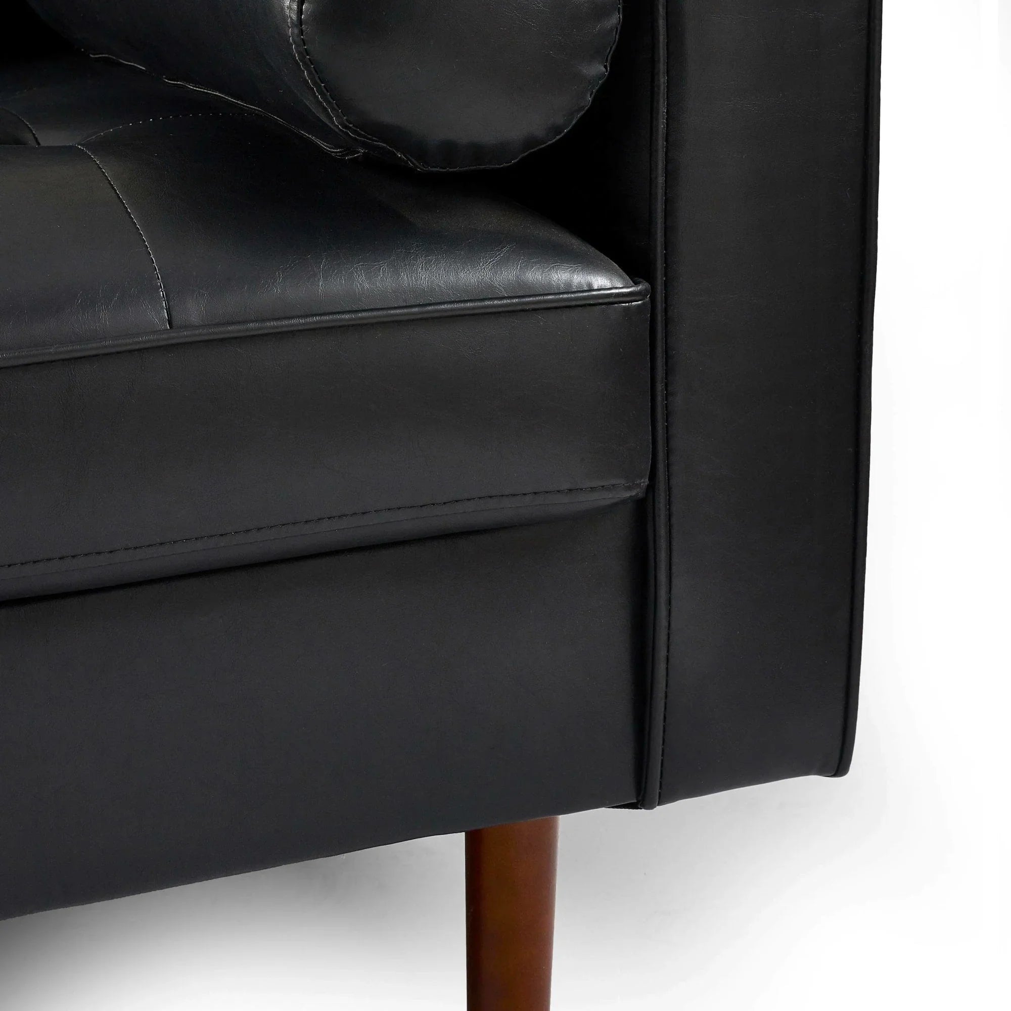 Close-up of black leather sofa cushion and armrest with wooden leg