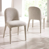Pair of cream boucle dining chairs with curved backs on tiled floor near window