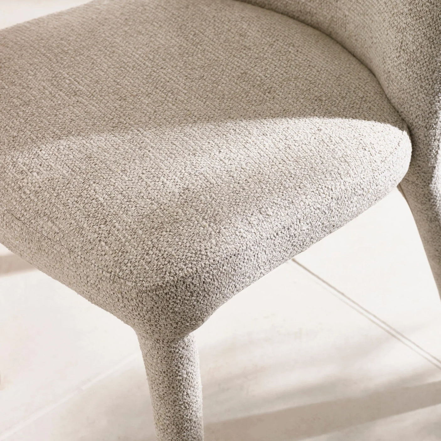 Close-up of beige fabric dining chair seat and textured upholstery on tile floor