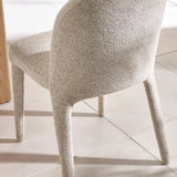 Beige boucle dining chair with curved backrest on tiled floor