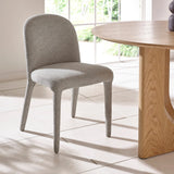 Light grey upholstered dining chair beside wooden round table on tiled floor