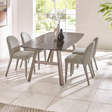 Glass dining table with taupe legs and four grey upholstered dining chairs in bright room