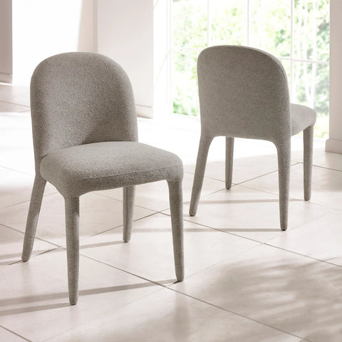 Pair of grey fabric dining chairs with curved backs on tiled floor by a window