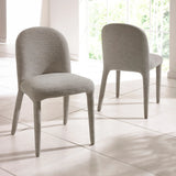 Pair of grey fabric dining chairs with curved backs on tiled floor by a window