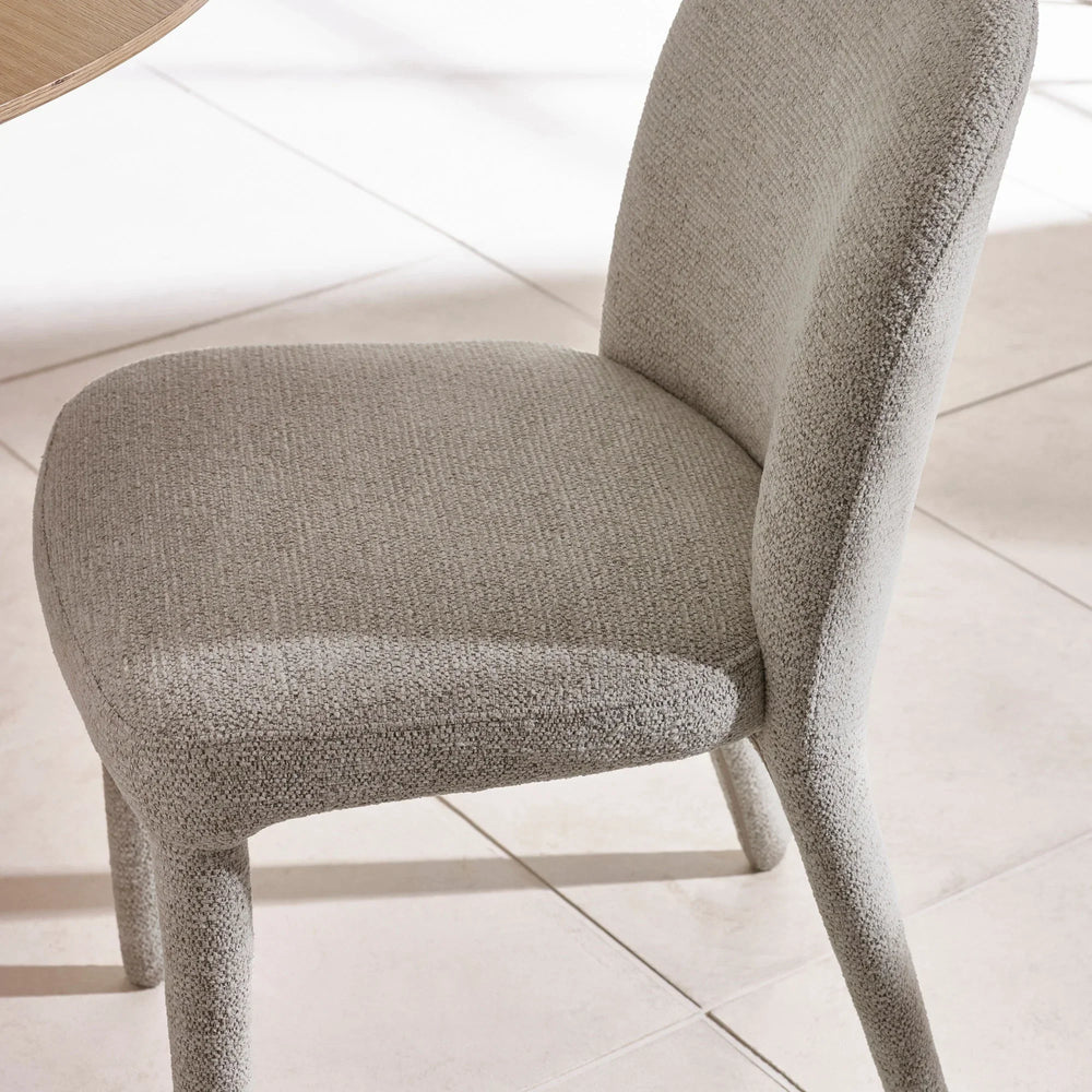 Light grey fabric dining chair with curved backrest on tiled floor