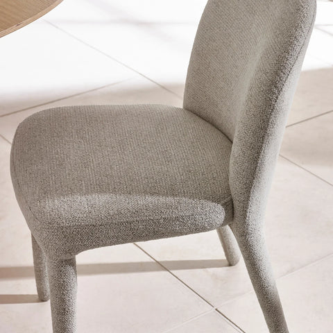Light grey fabric dining chair with curved backrest on tiled floor