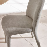 Light grey fabric dining chair with curved backrest on tiled floor