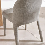 Light grey boucle dining chair with curved backrest on tiled floor
