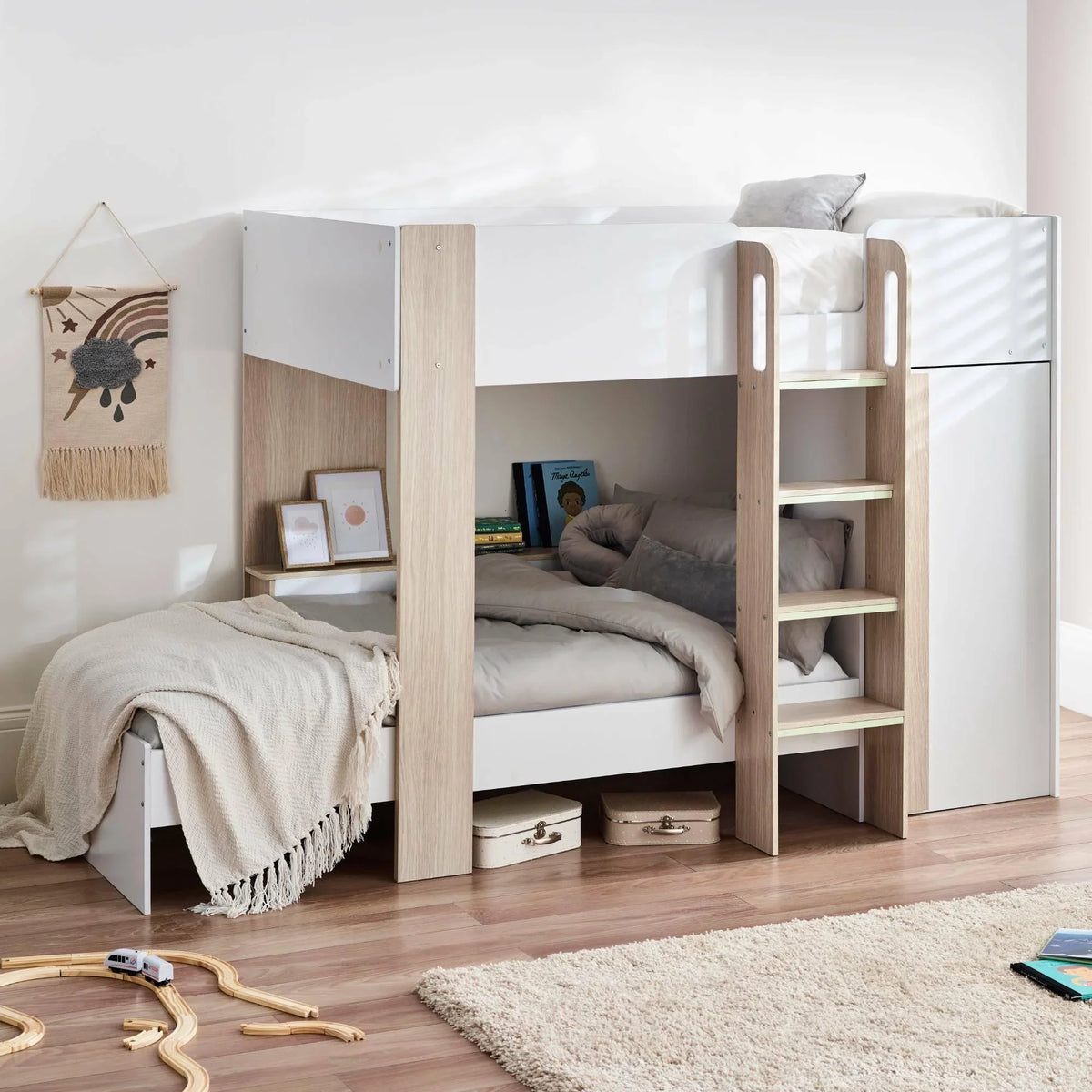 Pale wood and white bunk bed with ladder, bedding, storage boxes, and books in a cozy kids' room