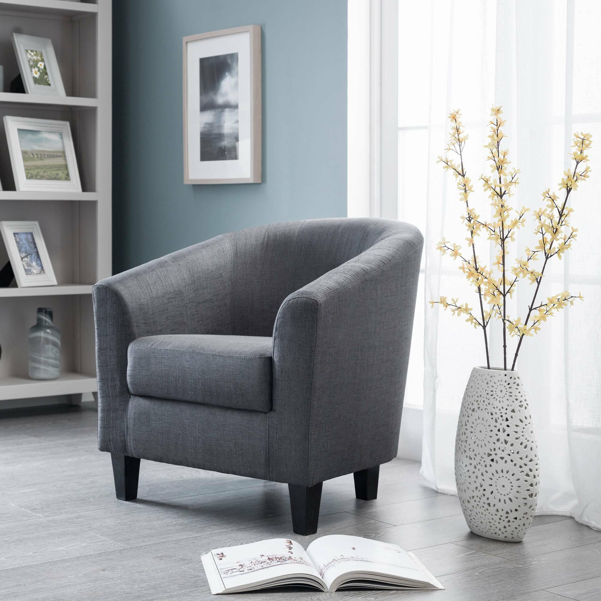 Slate grey tub chair with fabric upholstery in a modern living room beside window and vase