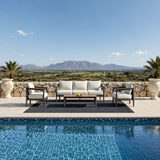 Beige cushioned wooden framed outdoor sofa set with black rug by blue pool | Home Centre Direct UK