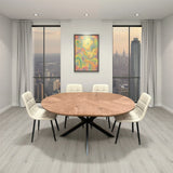 Round extension dining table with wooden top and black legs, surrounded by cream chairs