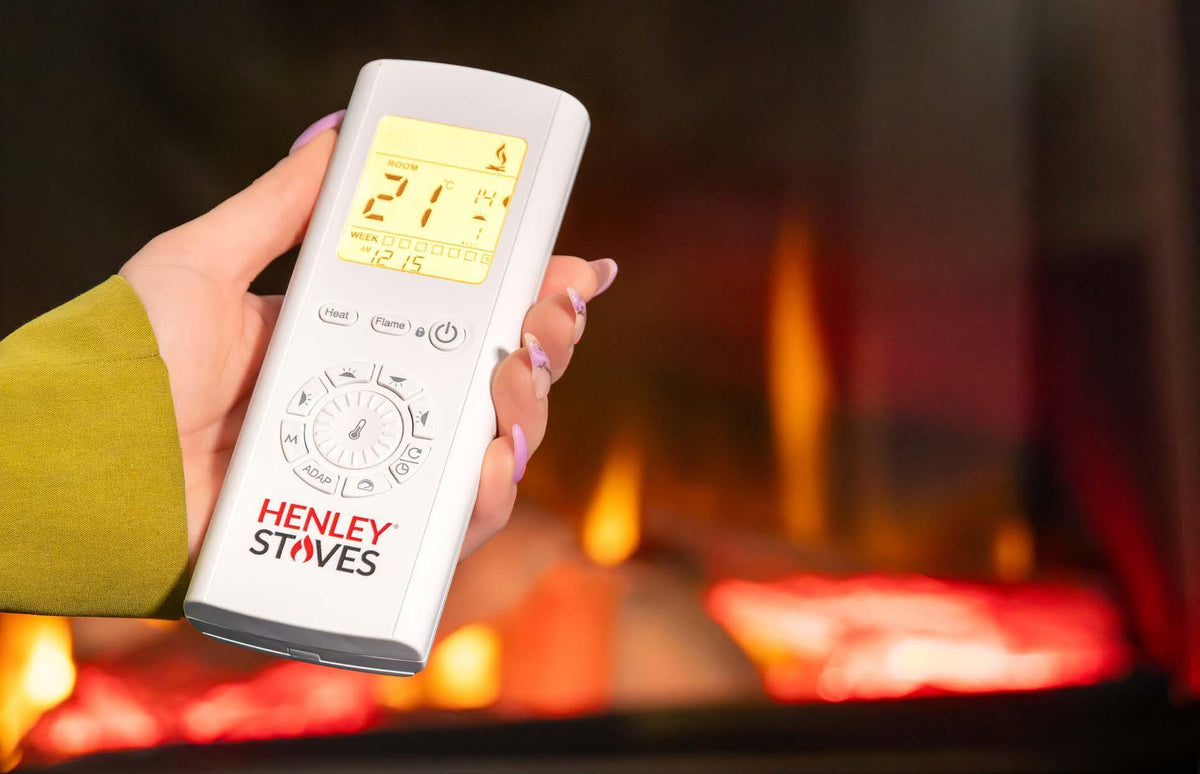 Electric stove remote control with digital display in hand, blurred flame background