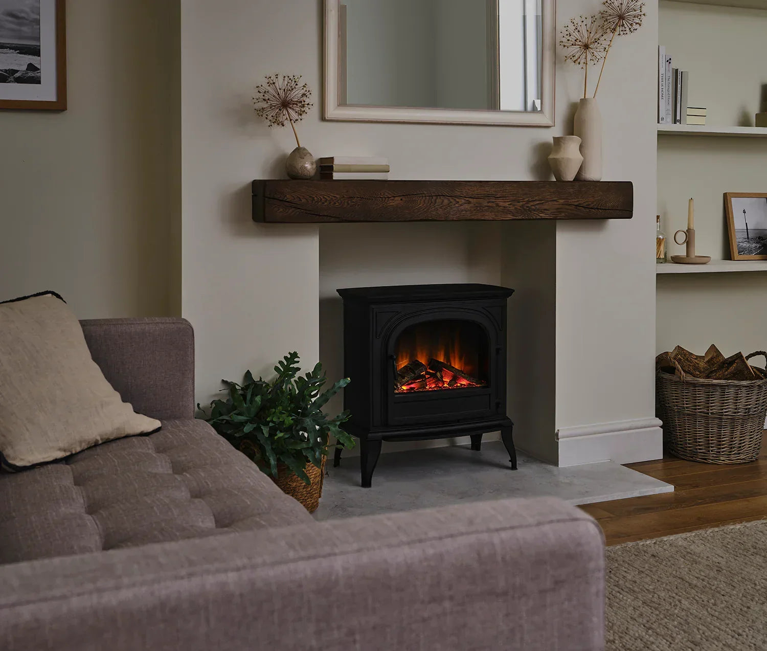 Black electric stove heater in modern living room with sofa, wooden mantel, and decor